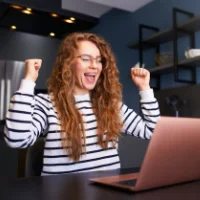 woman at computer with loan application excited becasue she was approved for her refinance