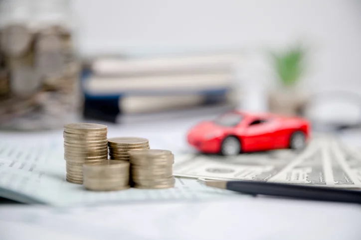 Red toy car on a desk with coins and paper money