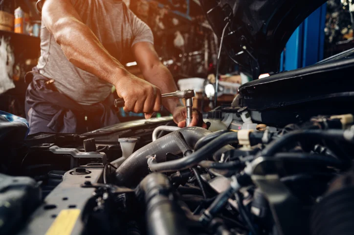 A mechanic under the hood working on a car engine