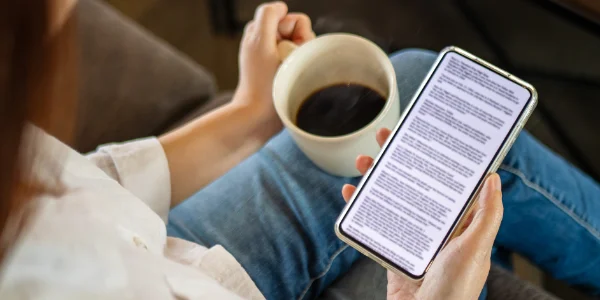 A woman relaxing at a desk drinking coffee and reading the Cuvrd refinancing guide